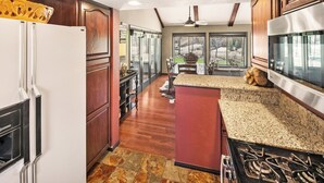 A kitchen with wooden cabinets, a granite countertop, a stove, and a dining area with a table and chairs.