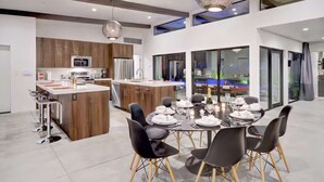 A modern kitchen with wooden cabinets, a central island, and a dining area with a round table set for six.