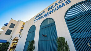 A building with the sign "Sugar Beach Condominiums" and large arched windows. - BEACH VIEW! One Bedroom at Sugar Beach Condos (Orange Beach)