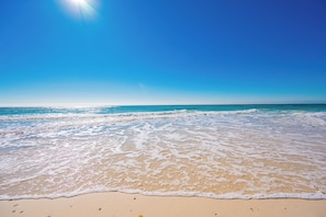 A beach with clear blue water and a sandy shore.