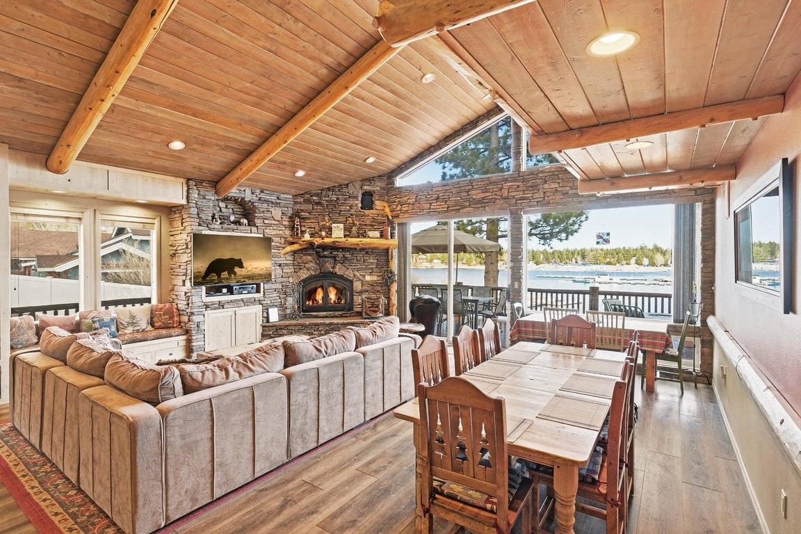 A cozy interior with a stone fireplace, wooden ceiling, and a large seating area.