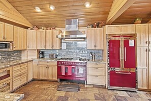 A kitchen with wooden cabinets, a red refrigerator, a stove, and a microwave. - Destro's Lakefront by Destination Big Bear : Luxury Lakefront! HOT TUB! PET FRIENDLY 🐾! Pool Table! WiFi! EV Charger! (Big Bear Lake)