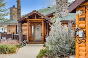 Una cabaña de troncos con chimenea de piedra, una puerta de madera y el número 451 en la fachada.