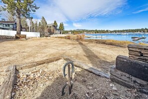 Un patio trasero con una terraza de madera, una reja de metal y vistas a un lago con barcos.