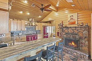 Una cocina con chimenea de piedra, armarios de madera y una zona de bar.
