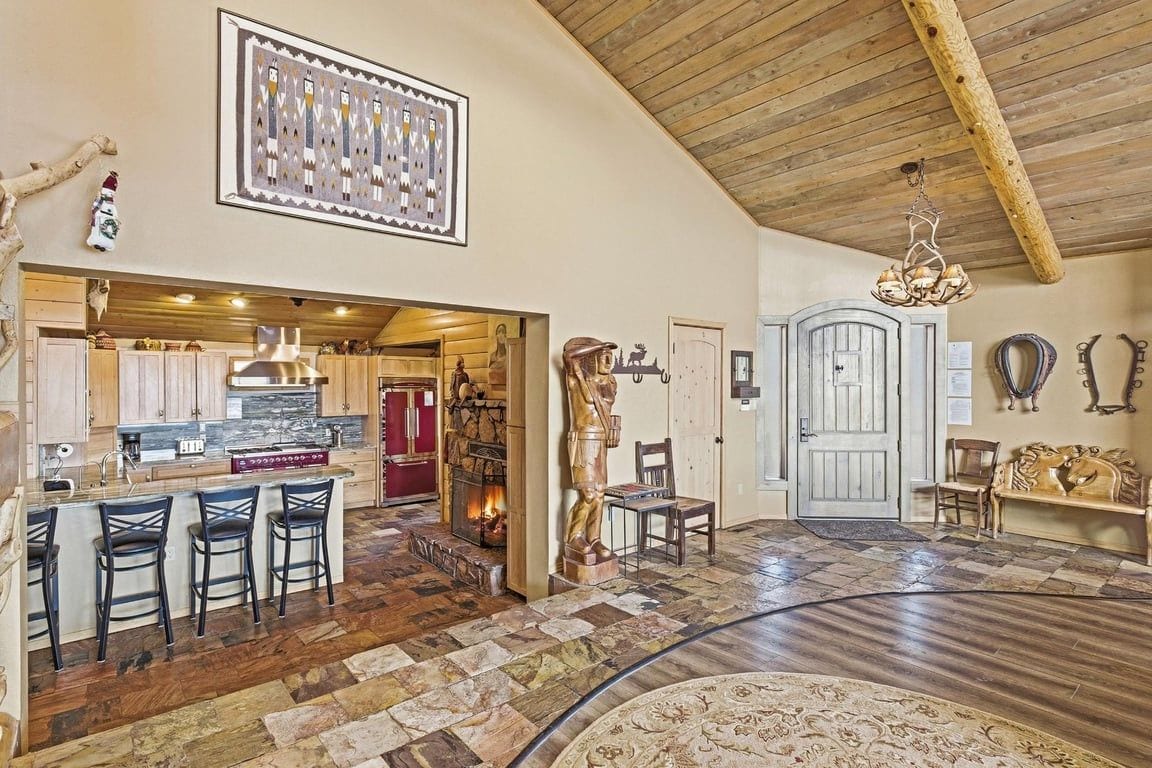 Ein großzügiger Wohnbereich mit Steinfußboden, Kamin, Holzboden und einer Bar mit Hockern.