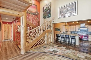 A wooden staircase with a unique design, a kitchen area with a bar, and a patterned floor.