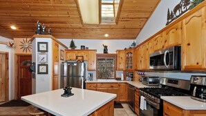 Una cocina moderna con armarios de madera, electrodomésticos de acero inoxidable y una isla central.