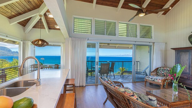 Un amplio salón con vistas al océano, un comedor con un ventanal grande y un balcón con mobiliario de exterior.