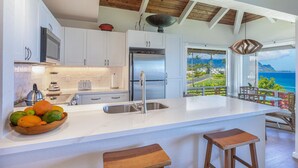 Una cocina moderna con una isla grande, electrodomésticos de acero inoxidable y vista al océano.