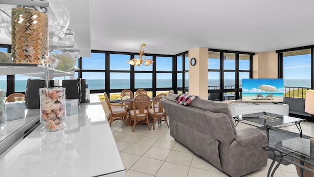 Ein modernes Wohnzimmer mit großem Fenster, einer Couch, einem Esstisch und einem Fernseher.