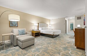 A hotel room with a bed, a sofa, a desk, and a chair.