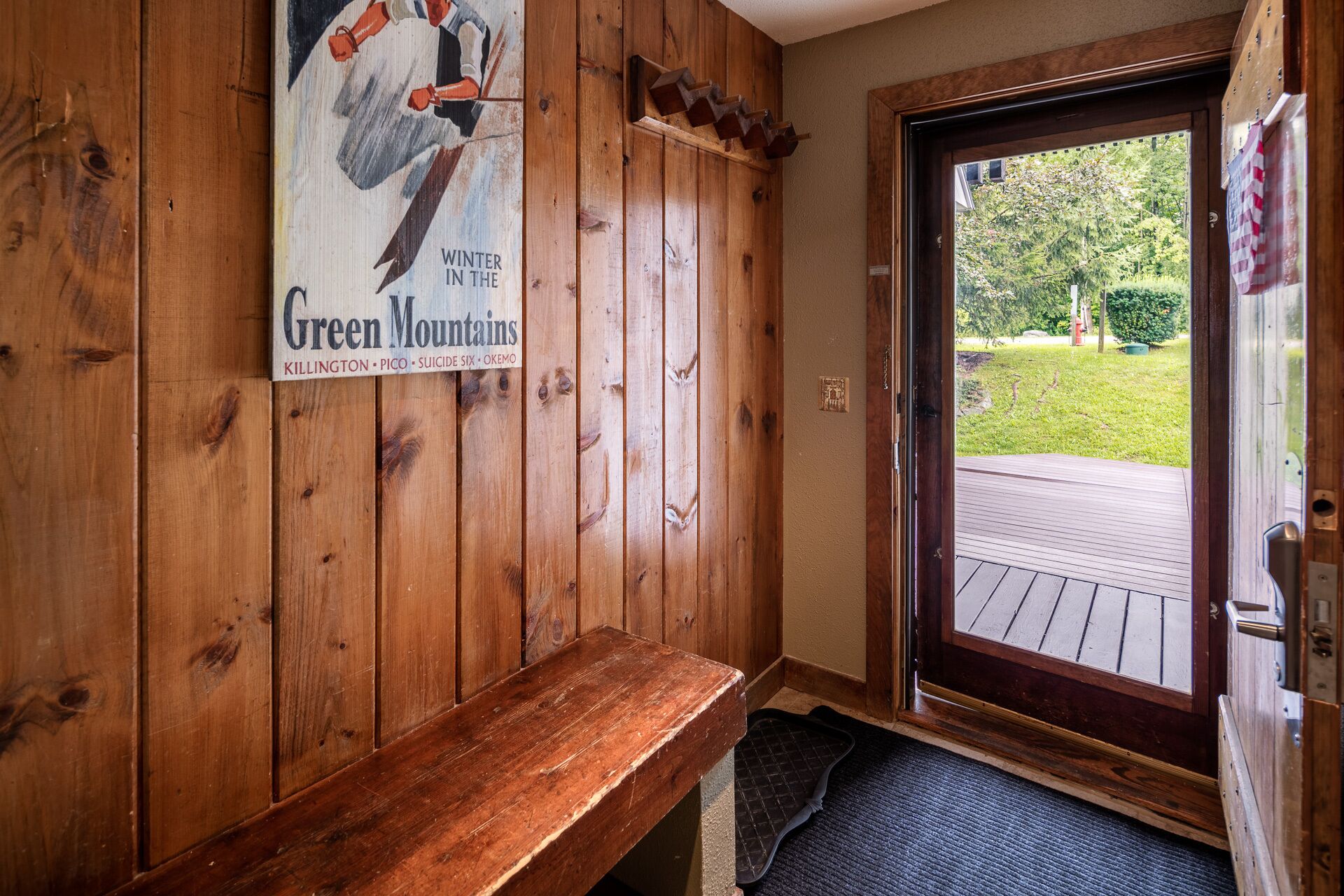 A wooden interior with a bench and a door leading outside.
