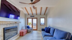 Ein Wohnzimmer mit Kamin, einem blauen Sofa und einem Deckenventilator.