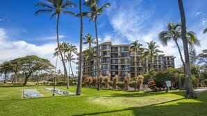 Un hôtel à plusieurs étages, doté d’un design moderne, entouré d’une végétation luxuriante et de palmiers.