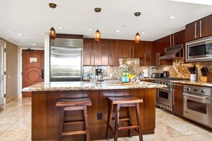 A modern kitchen with a large island, stainless steel appliances, and wooden cabinetry. - Honua Kai | Ocean View 3 BR | Car Incl. w/ 6+ Nights | HKH-503 by KBM (Lahaina)