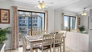 Un comedor con una mesa y sillas, un ventilador de techo y vistas al balcón exterior.