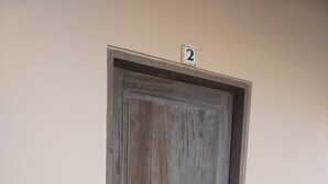 A wooden door with a number plate indicating room 2, a keyhole, and a light switch on the wall. - Hacienda de Palmas: Room #2 Cupola with one queen size bed (La Ribera)