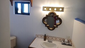 A bathroom with a toilet, sink, and a mirror with lights. - Hacienda de Palmas: Room #2 Cupola with one queen size bed (La Ribera)