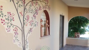 A covered patio with a mural of a tree and two statues, a round table, and two chairs. - Hacienda de Palmas: Room #2 Cupola with one queen size bed (La Ribera)