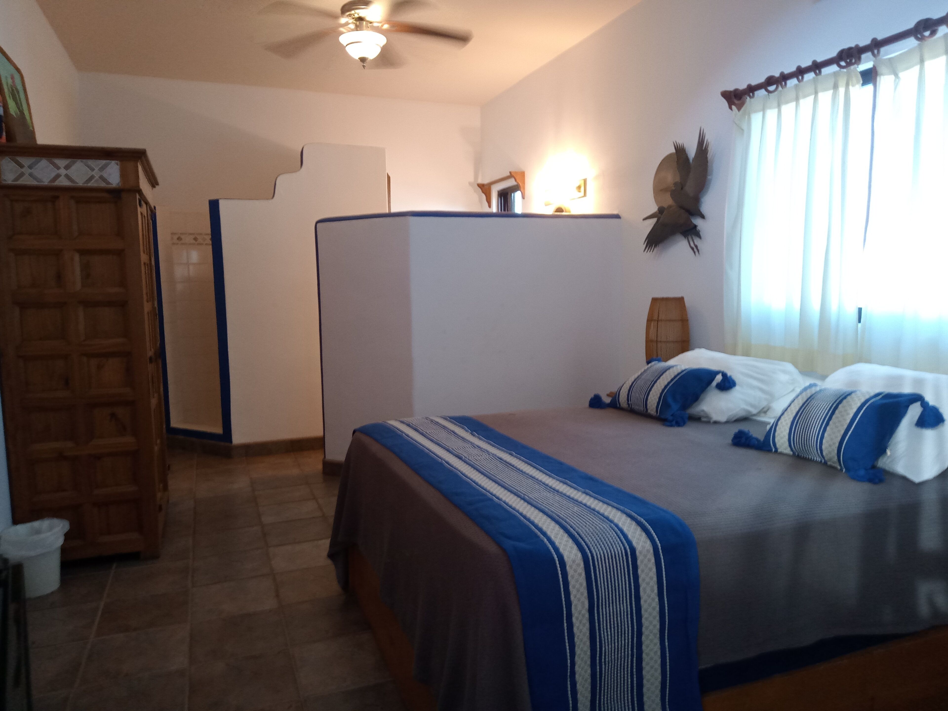 Un dormitorio con cama, armario, escritorio y ventilador de techo.