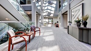 A spacious indoor area with a high ceiling, glass railings, and multiple seating areas. - Woods  Resort Village 10 Cozy Killington Escape –1BR + Loft, Fireplace, Pool & Hot Tub Access (Killington)