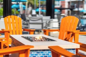 Outdoor seating with orange chairs and a fire feature.