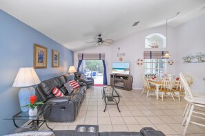 Un salon comprenant un canapé, une table basse et un téléviseur. Il y a également un coin repas avec une table et des chaises.