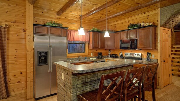 A kitchen with wooden walls, a refrigerator, a microwave, a coffee maker, and a sink. - Serenity Lodge: Theater, Gameroom, Hot Tub (Gatlinburg)