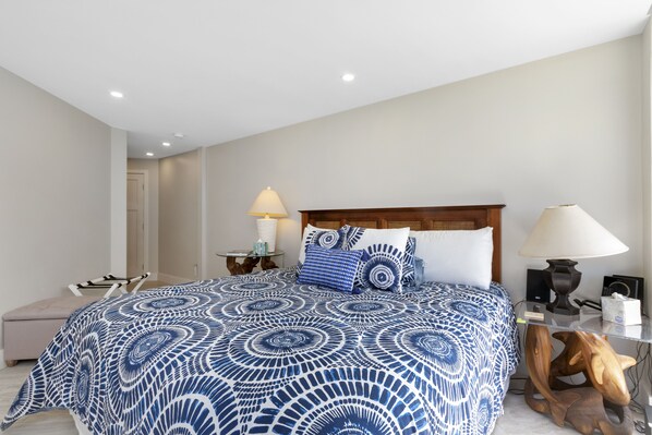 A bedroom with a large bed, a wooden headboard, a bedside table with a lamp, and a small table with a lamp.