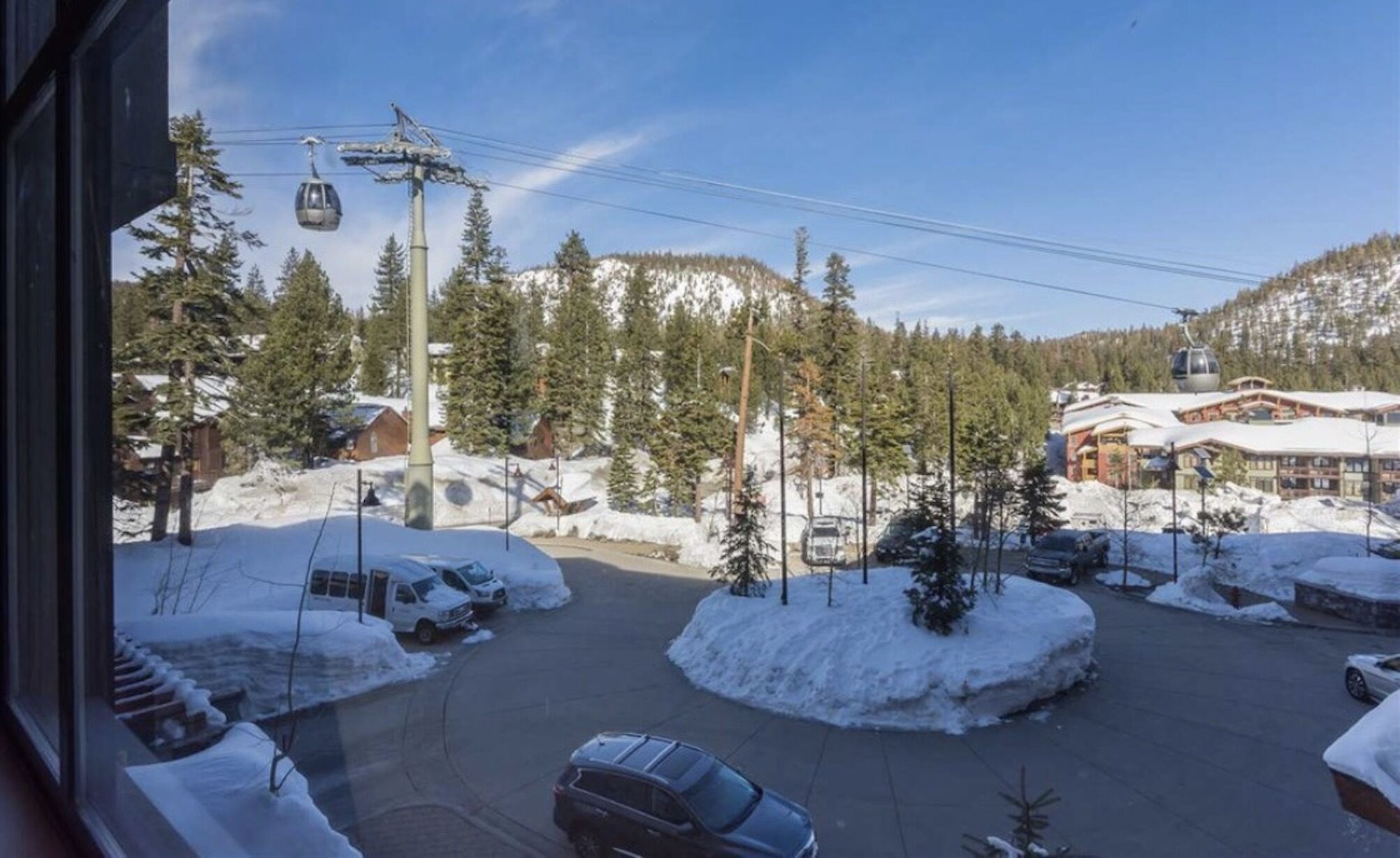 Una località sciistica con un'area parcheggio, una seggiovia e edifici dalle tegole imbiancate dalla neve.