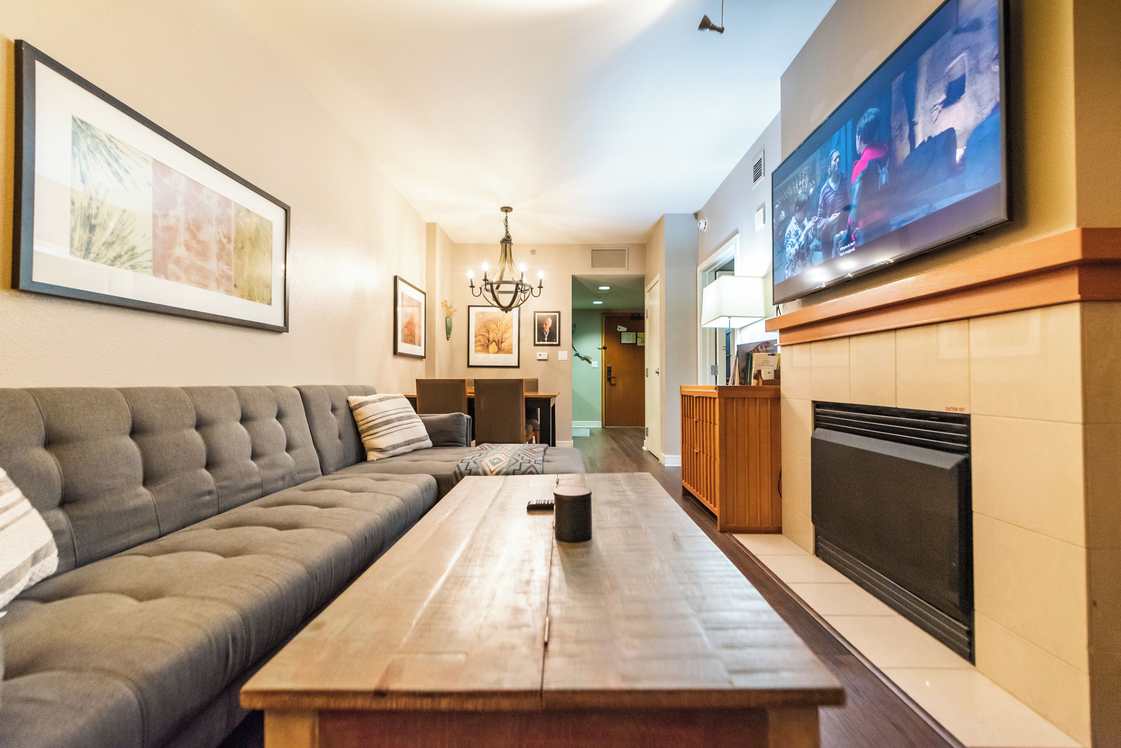 Una sala de estar con sofá, mesa de centro, chimenea y televisor montado en la pared.