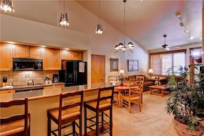A modern kitchen with wooden cabinets, a central island with bar stools, and pendant lighting.