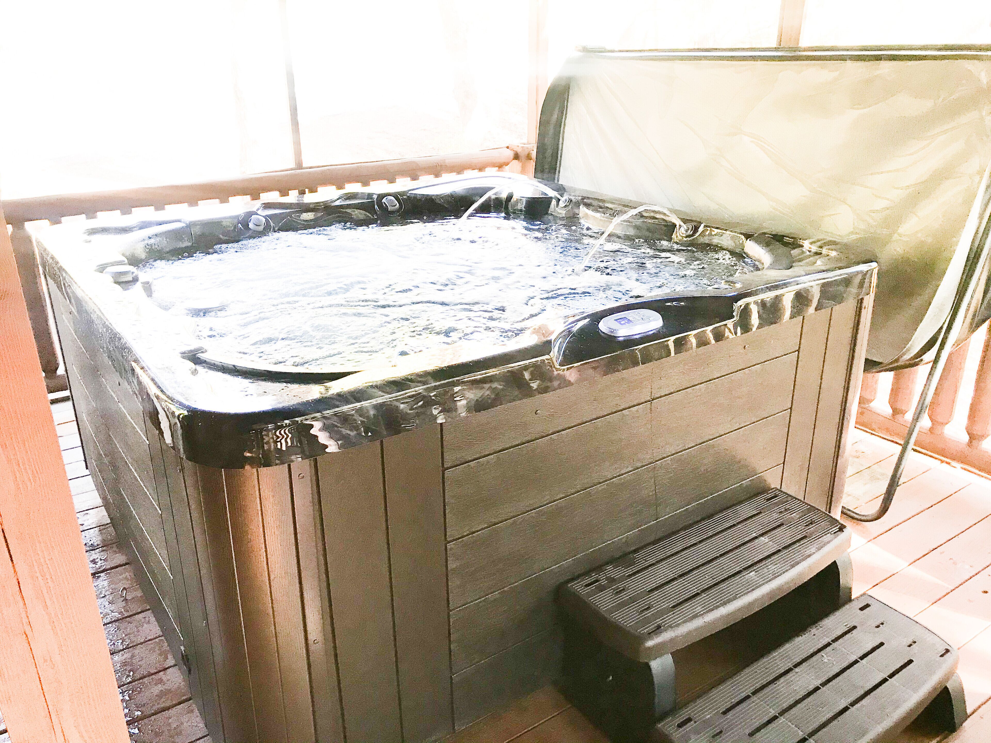 A hot tub with a control panel, a bench, and a covered area.
