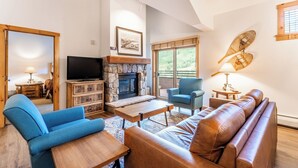 A spacious living room with a stone fireplace, a television, and comfortable seating. - Ideal Location in River Run, Beautiful Mountain Views, Close to Gondola/Shops (Keystone)