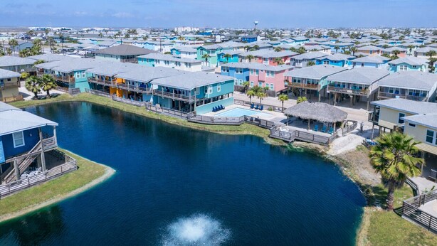 A coastal residential area with houses along a water body, featuring balconies and a swimming pool. - Come stay and play at the Cherry on Top, Ocean Village’s premier rental! Private (Port Aransas)