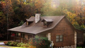 Eine Blockhütte mit einem Steinkamin, einer Veranda und einem kleinen Anbau.