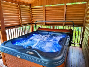 Ein Whirlpool mit Bedienfeld, umgeben von Holzwänden und einer Holzterrasse.