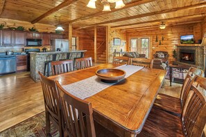 Cozy cabin interior with a dining table, fireplace, and modern kitchen.