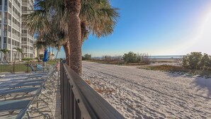 A beach with a wooden walkway, palm trees, and a building with balconies. - 2B/2B Beachfront Island Vacation Condo at Creciente w/ View of Gulf and Pool (Fort Myers Beach)