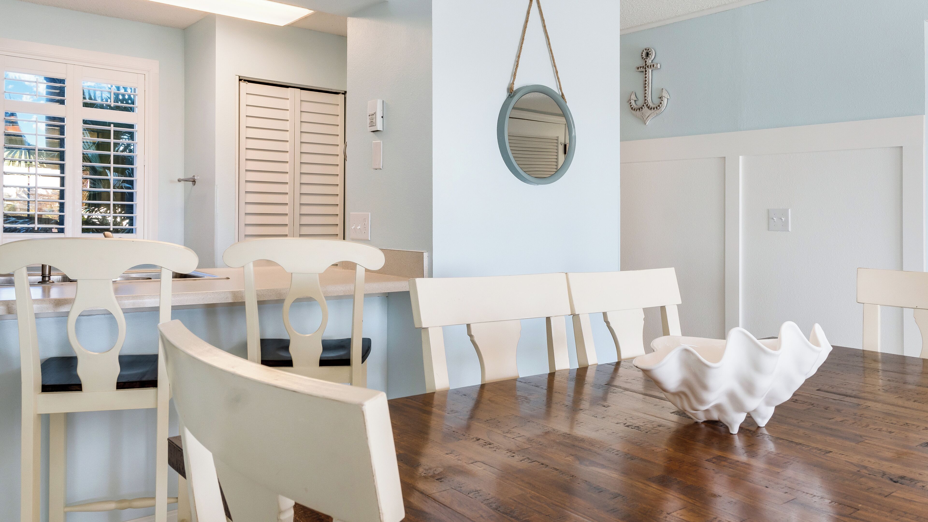 A dining area with a wooden table, white chairs, and a decorative bowl.