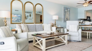 Un salon comprenant un canapé, des fauteuils, une table basse et un coin repas avec une table et des chaises.