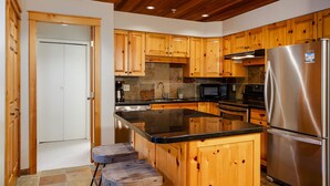 Una cocina moderna con armarios de madera, un refrigerador de acero inoxidable, un microondas y una cafetera.