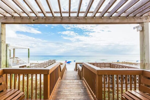Walk along the boardwalk to the ocean, flanked by benches and railings.
