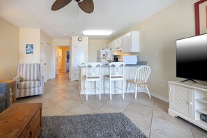 Una sala de estar con un sofá, un televisor y un comedor con sillas y una mesa.