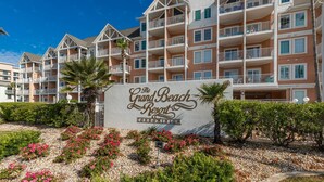 A sign for The Grand Beach Resort Condominium with a multi-story building in the background.