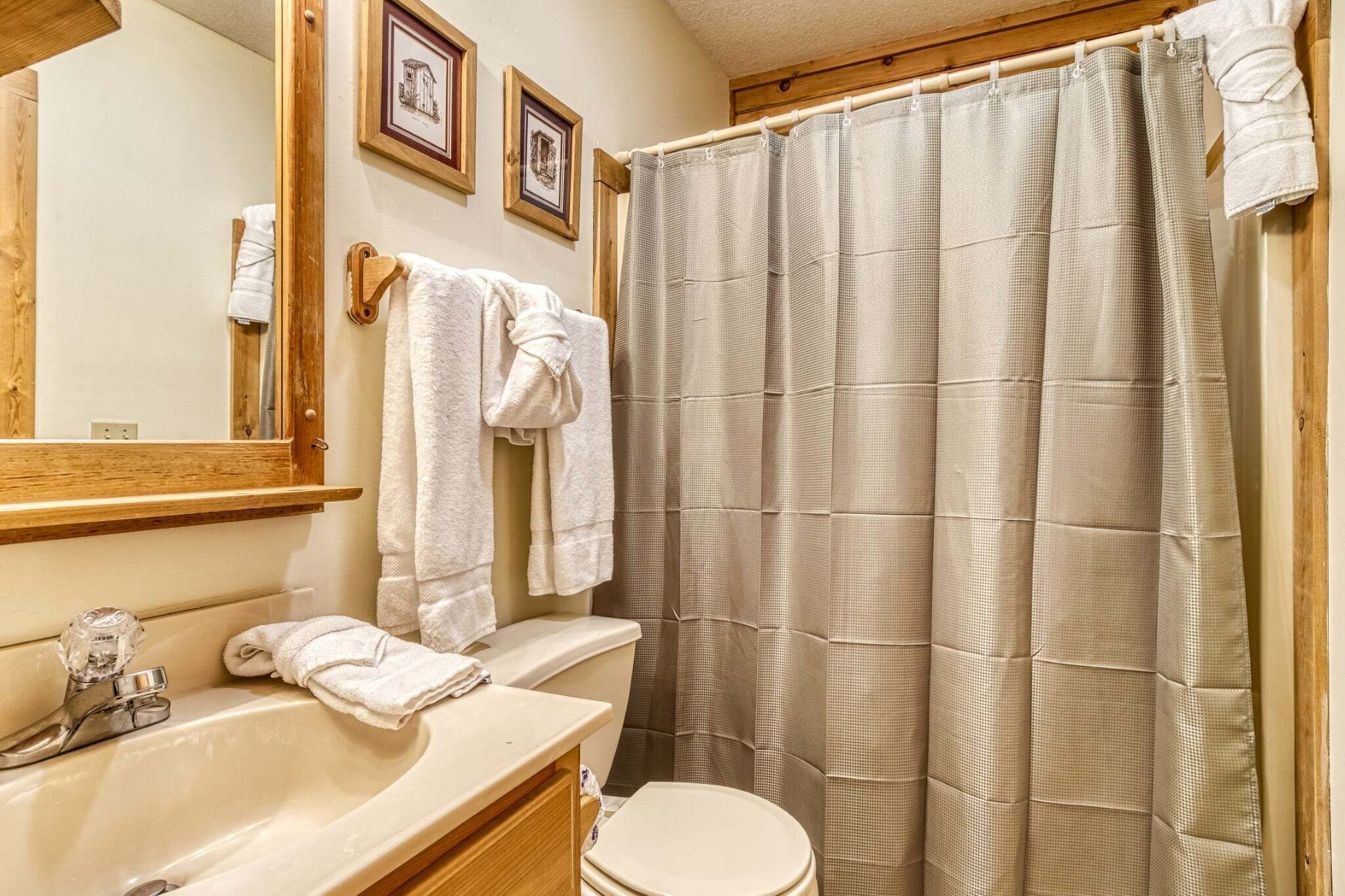 Un baño con lavamanos, espejo, inodoro y cortina de ducha.