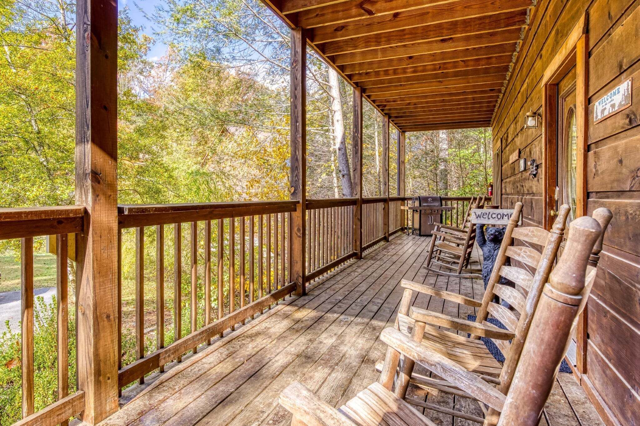 Une véranda en bois avec une balustrade en bois, un banc et une pancarte de bienvenue.