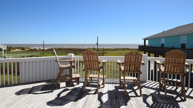 A wooden deck with Adirondack chairs overlooking a beach. - Chateau Des Fontenot (Bolivar Peninsula)