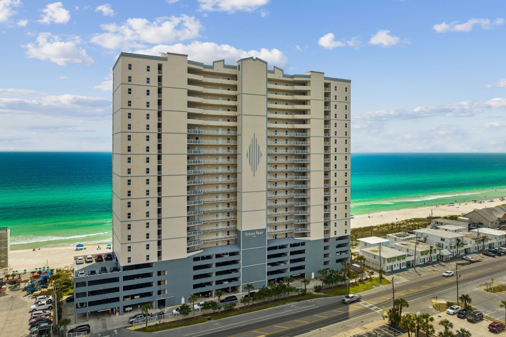 A high-rise hotel with multiple floors, a parking garage, and a view of the beach.